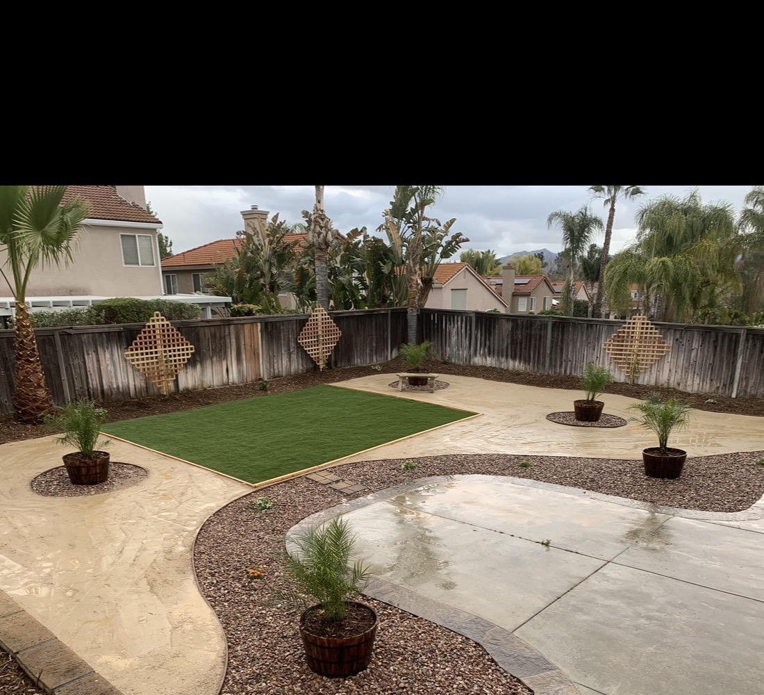 Complete backyard remodel with turf, decorative rock, concrete, and barrel planters