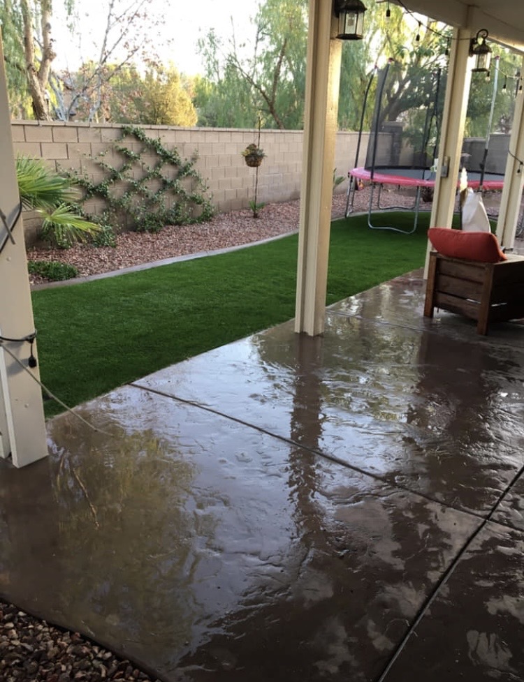 Backyard turf installation with stamped concrete patio and bark mulch border in Hemet