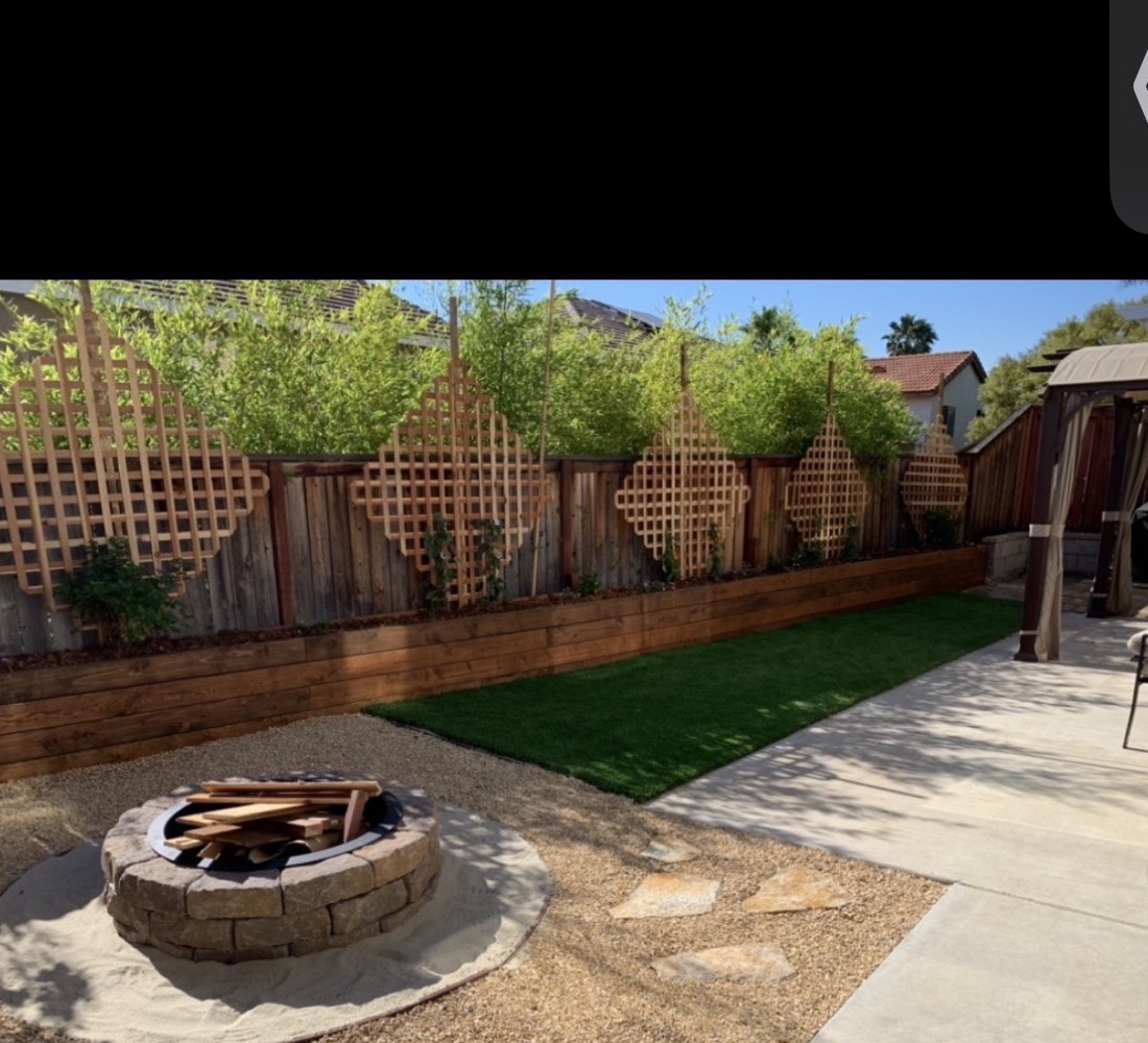 Fire pit with turf patch and trellis privacy wall in a backyard in Murrieta