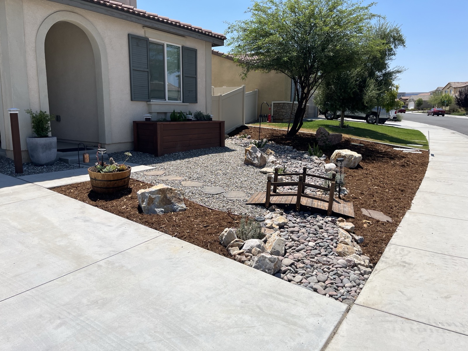 Front yard landscaping with wooden bridge, rock river, and planter box in San Jacinto