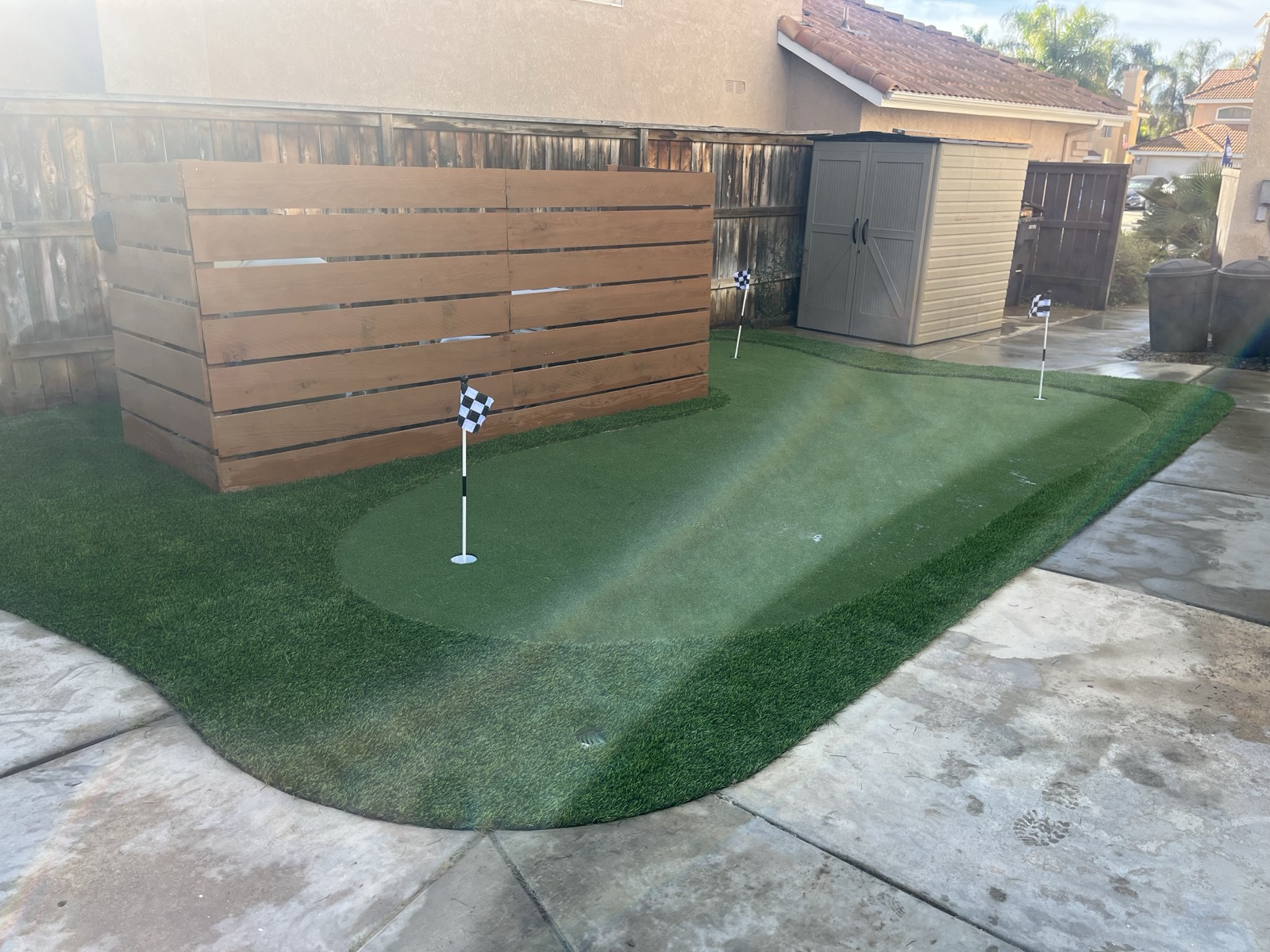 Custom putting green with checkered flags and wood privacy wall